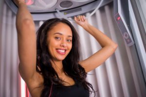 Smiling woman preparing for a red light therapy session at SunScape Tanning